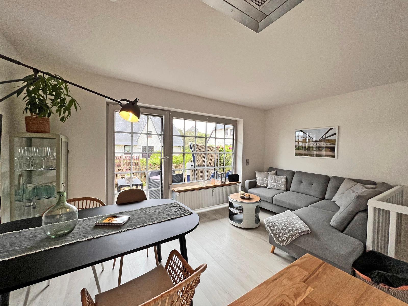 Wohn- und Essbereich mit Sofa, Tisch und Fenster zur Terrasse.