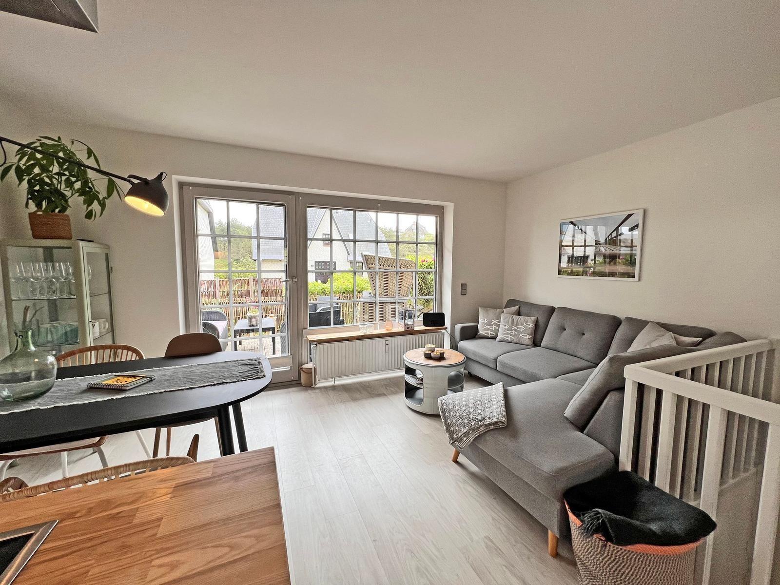 Wohn- und Essbereich mit Sofa, Tisch und Blick auf Balkon.