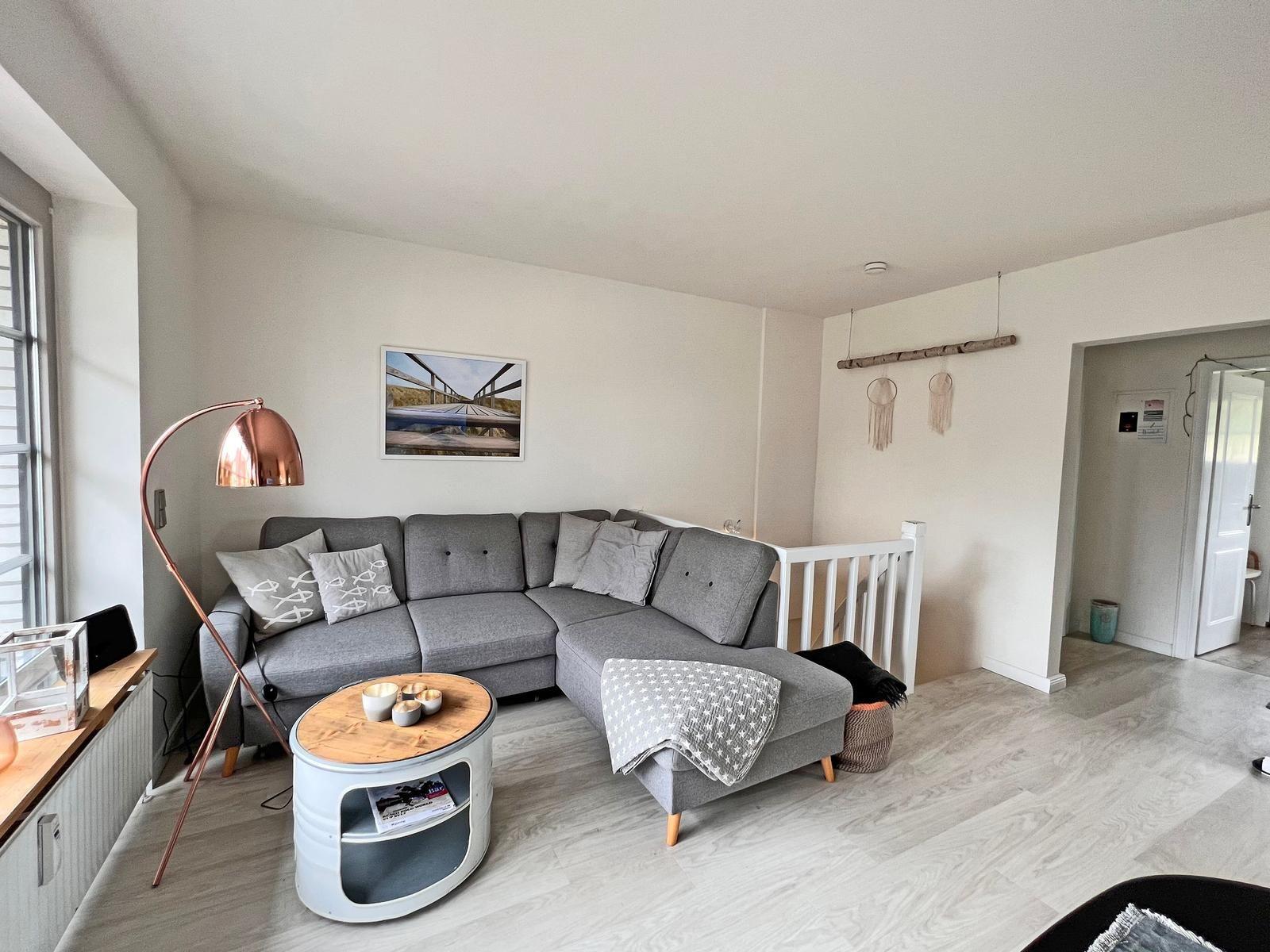 Wohnzimmer mit grauem Sofa, runden Tisch und Stehlampe.