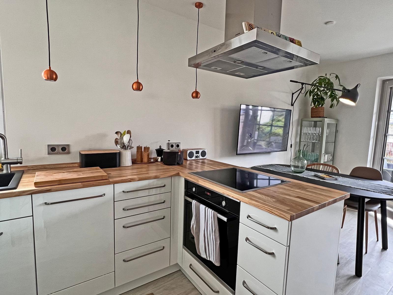 Küche mit Holzoberflächen, weißen Schränken und integriertem Herd.