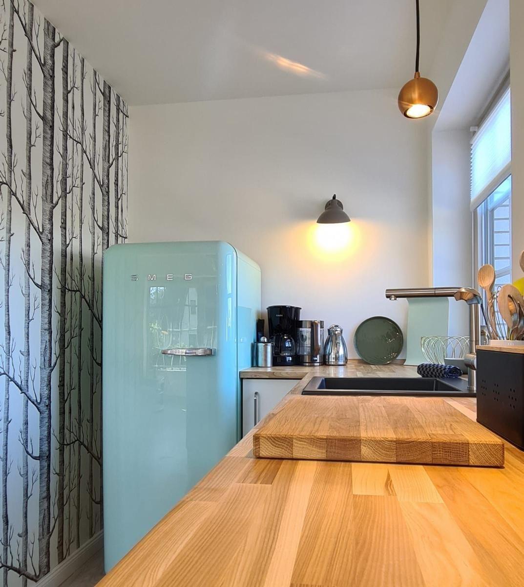 Küche mit Holzoberfläche, hellblauer Kühlschrank und Baum壁纸.