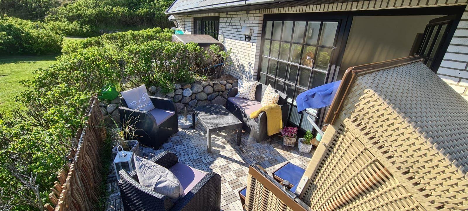 Terrasse mit Sitzgelegenheiten und Blick auf grünen Garten.