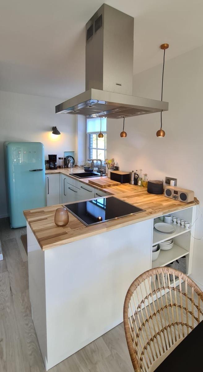 Küche mit Holz Arbeitsplatte, Edelstahl Dunstabzug und hellen Wänden.