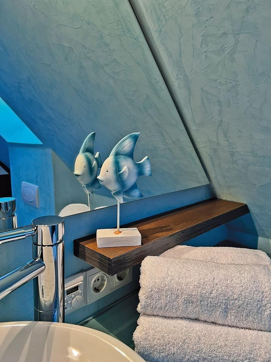 Badezimmer mit blauer Wand, Spiegel und Fischdekoration