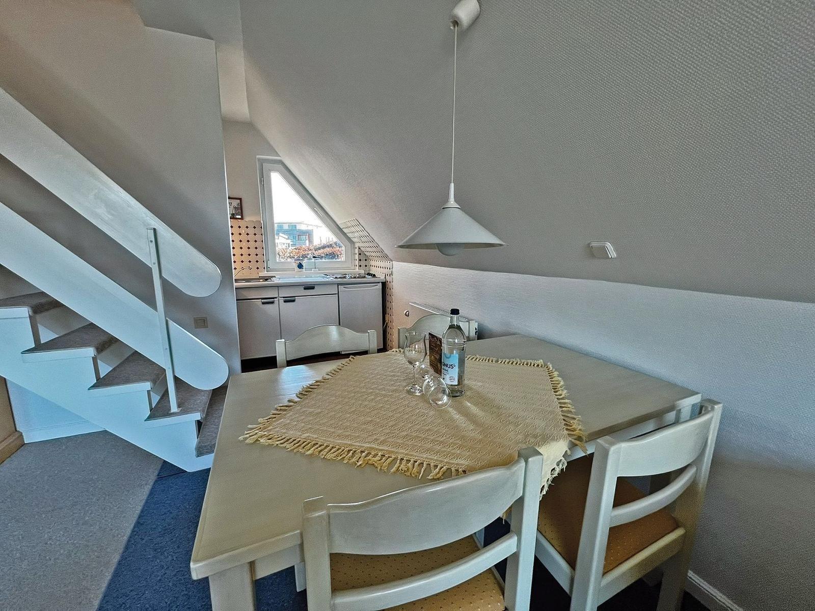 Essbereich mit Tisch, Stühlen und Blick in die Küche.