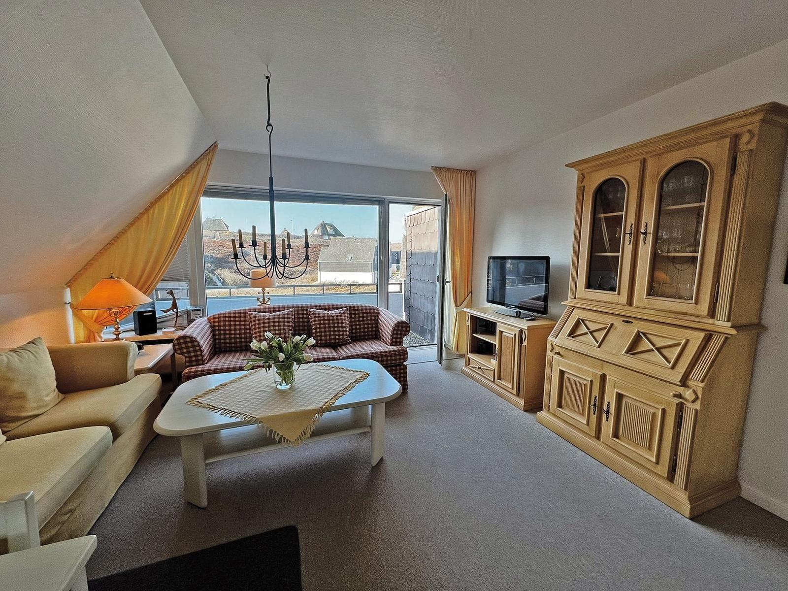 Wohnzimmer mit Sofa, Couch, Tisch und TV. Blick auf Balkon.