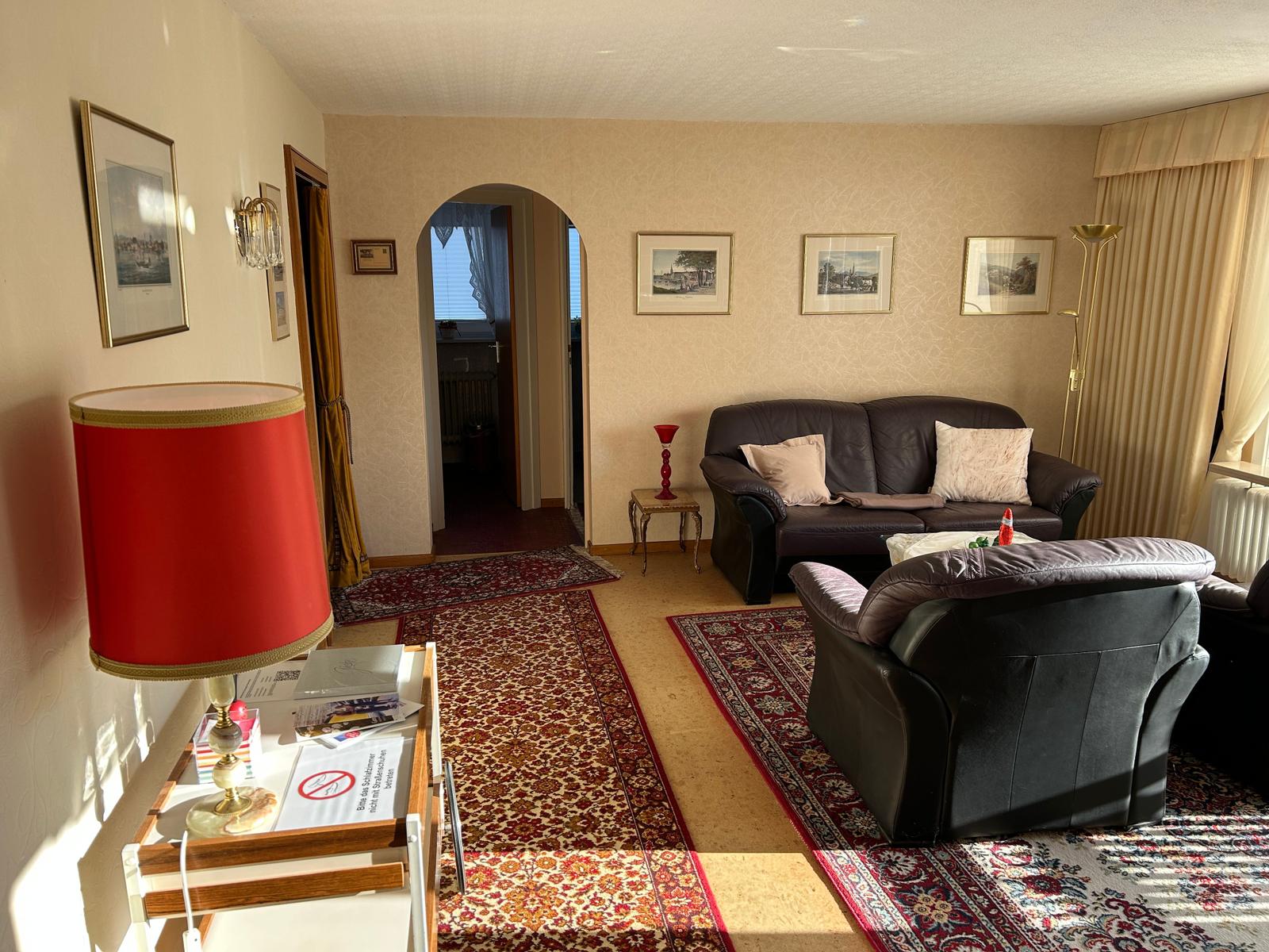 Wohnzimmer mit Ledersofa, Sessel, Teppichen und Wandbildern.