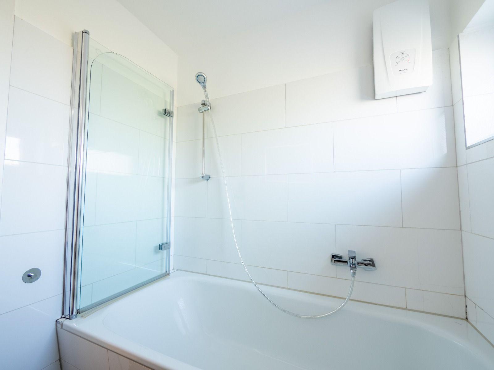 Badezimmer mit Badewanne und Duschkabine, Wandheizung und Fenster