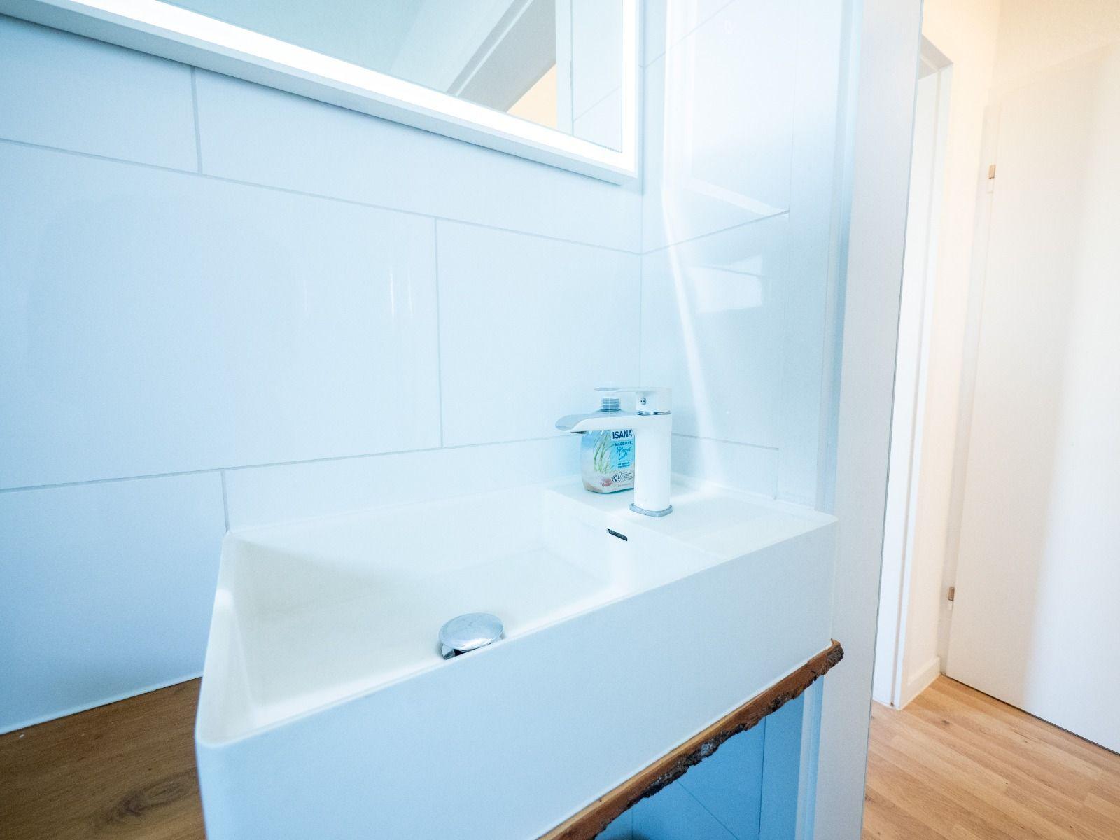Waschbecken mit Spiegel und Seifenspender an Wand