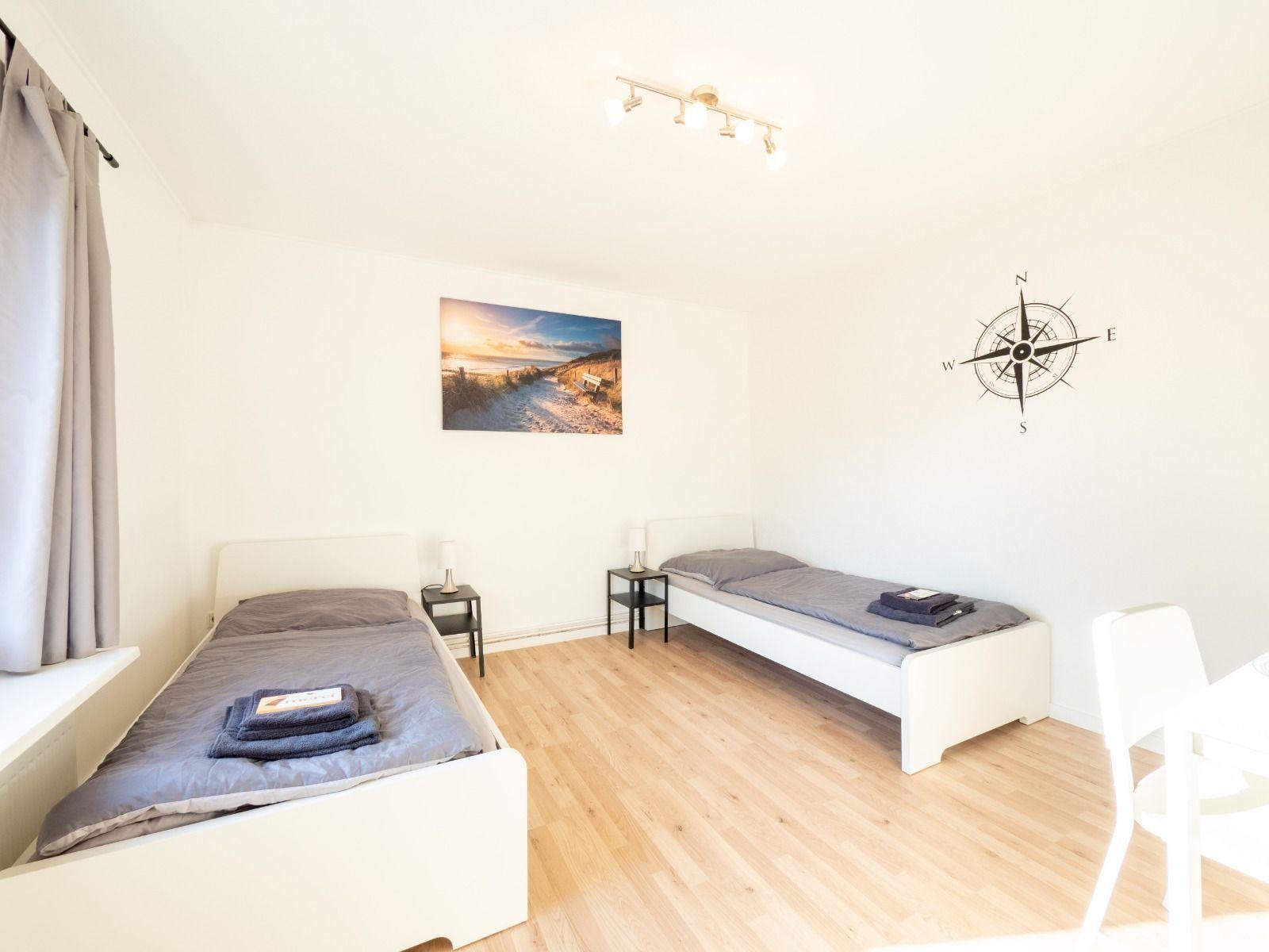 Zwei Einzelbetten, Wandbild und Kompass an der Wand