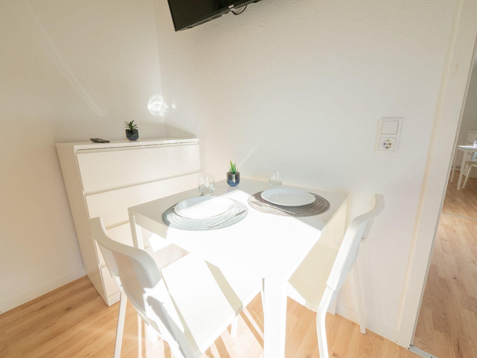 Essbereich mit weißem Tisch, zwei Stühlen und Platz für zwei Personen.
