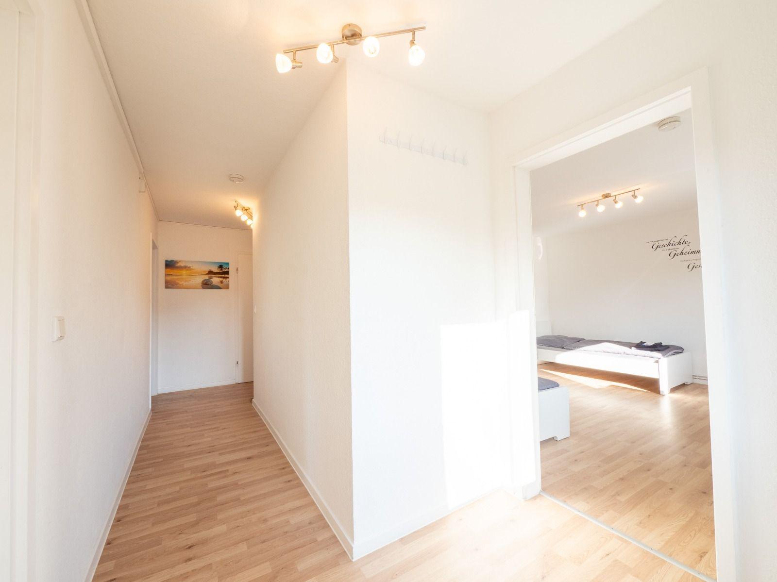 Flur mit Holzboden und Schlafzimmer mit Bett und Wanddekoration.