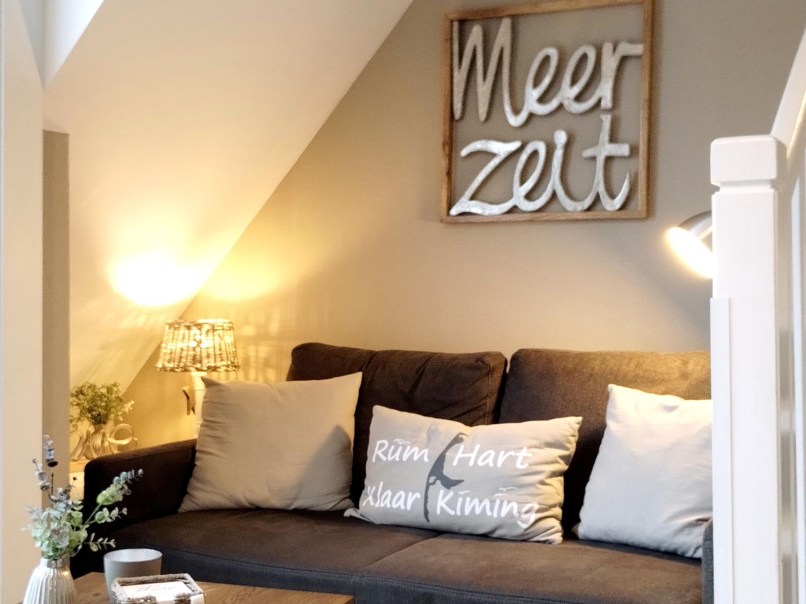 Ein Sofa mit Kissen unter einer Schrift an der Wand.
