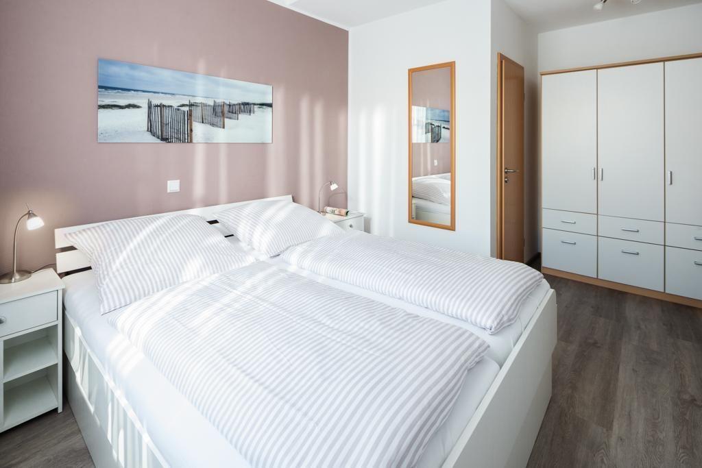 Schlafzimmer mit Doppelbett, Kleiderschrank und Wandbild.