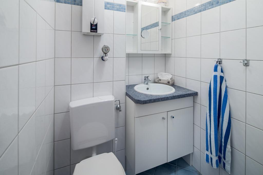 Badezimmer mit Toilette, Waschbecken und Spiegelschrank