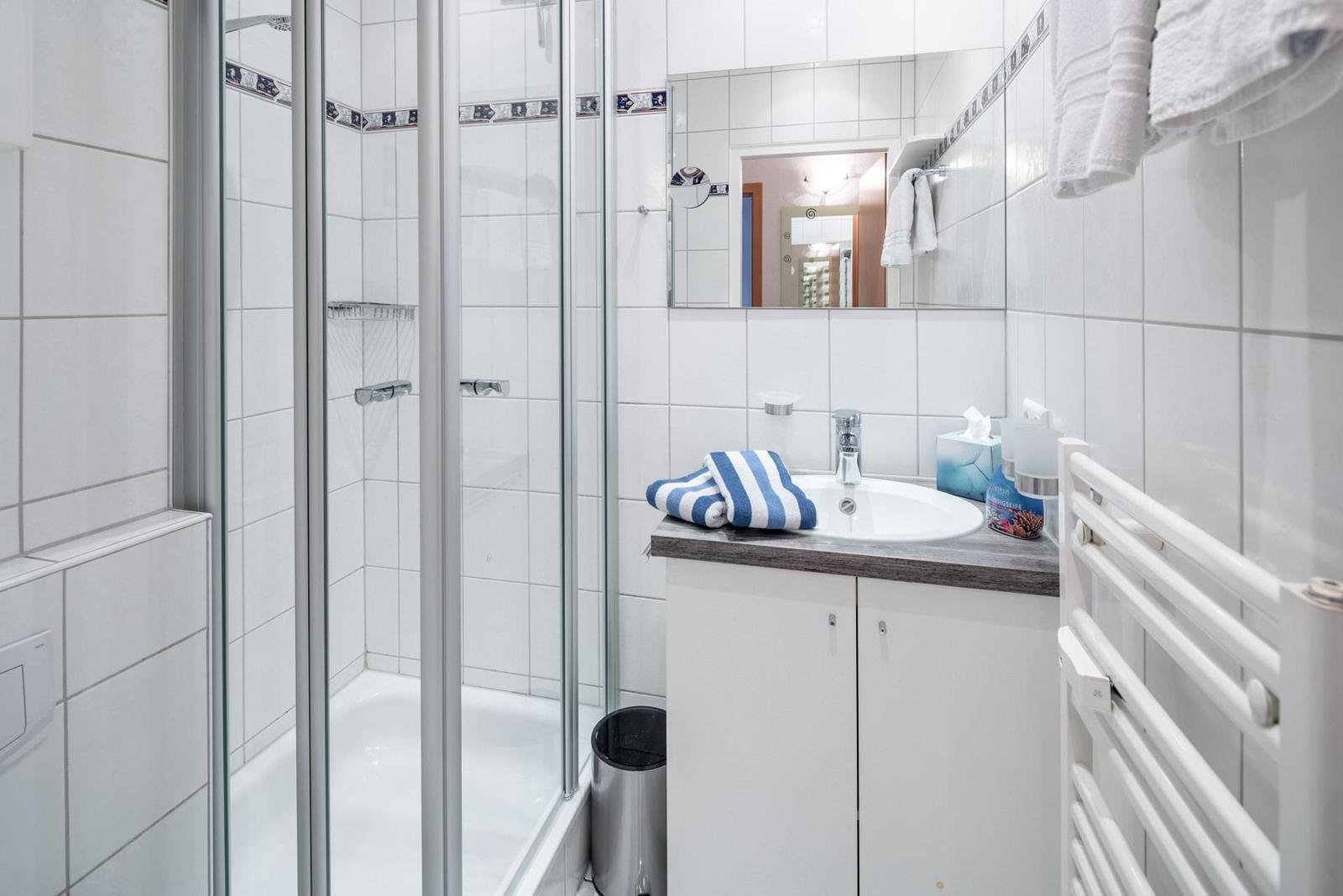 Badezimmer mit Dusche, Waschbecken und Handtuchheizung.