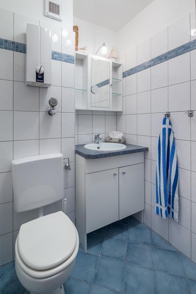 Badezimmer mit Toilette, Waschbecken und Duschmöglichkeit.