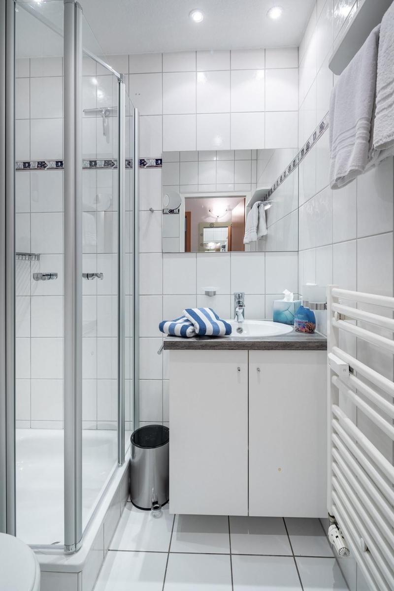 Badezimmer mit Dusche, Waschbecken und Heizung.