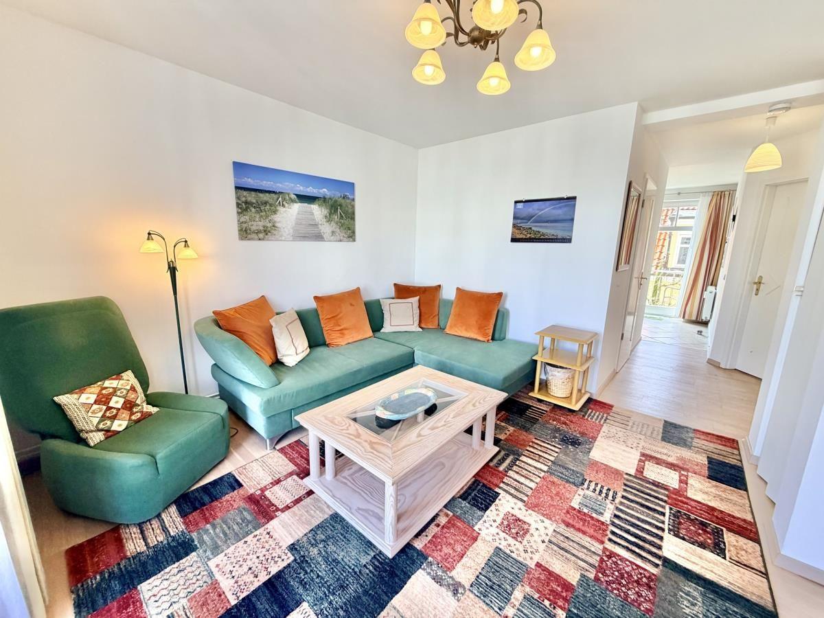 Ein Wohnzimmer mit grünem Sofa, gemustertem Teppich und Wandbildern.
