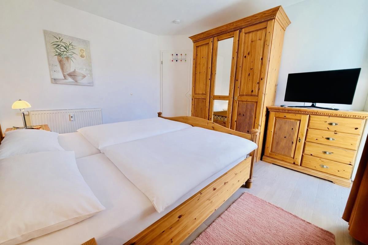 Schlafzimmer mit Bett, Kleiderschrank und TV