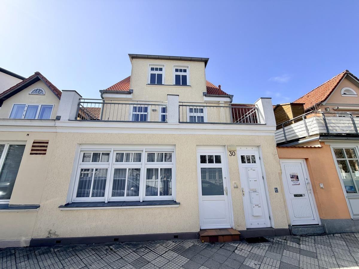 Haus mit Balkon und weißen Fenstern. Hausnummer 30. Terrakottadach.