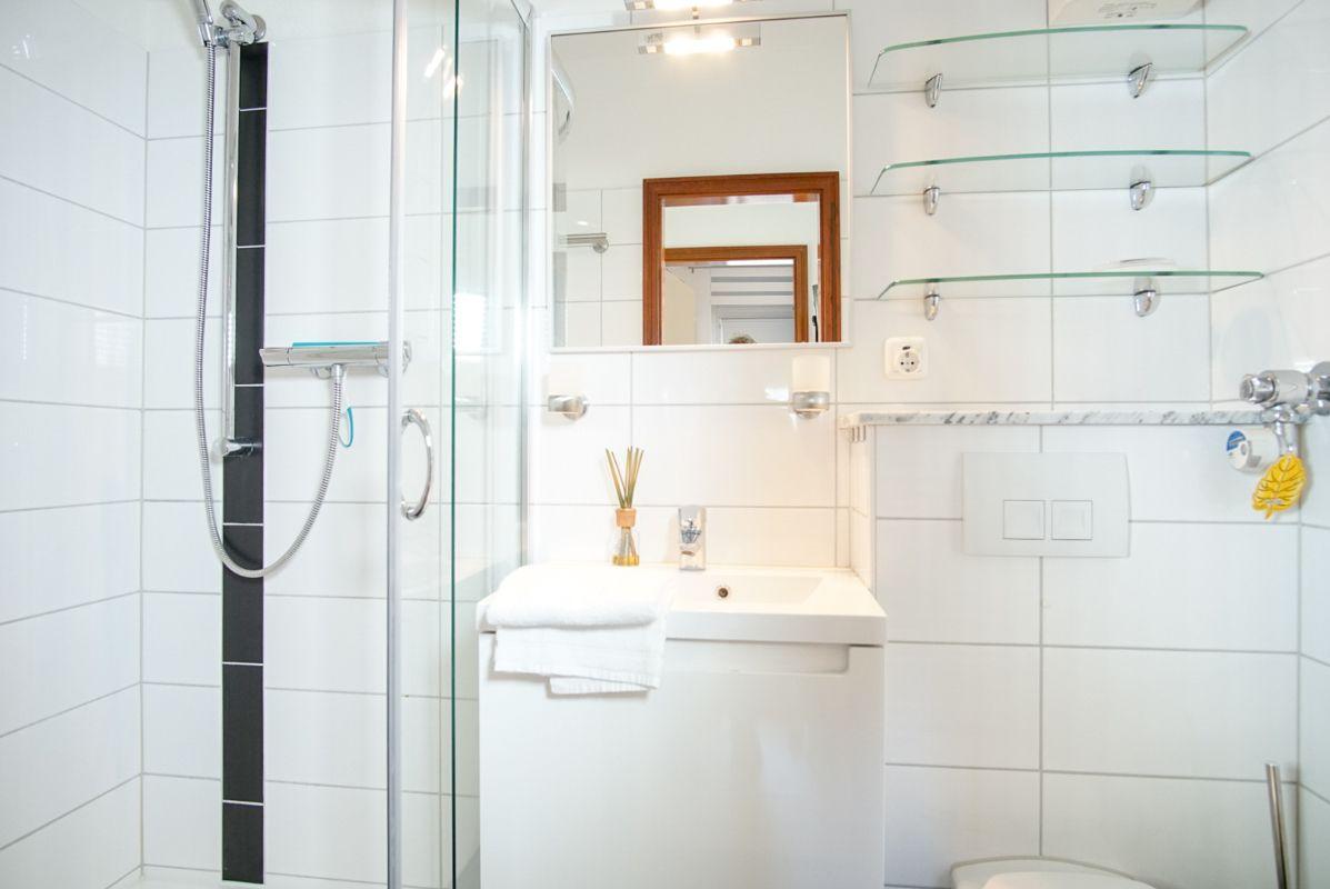 Badezimmer mit Dusche, Waschbecken und Spiegel