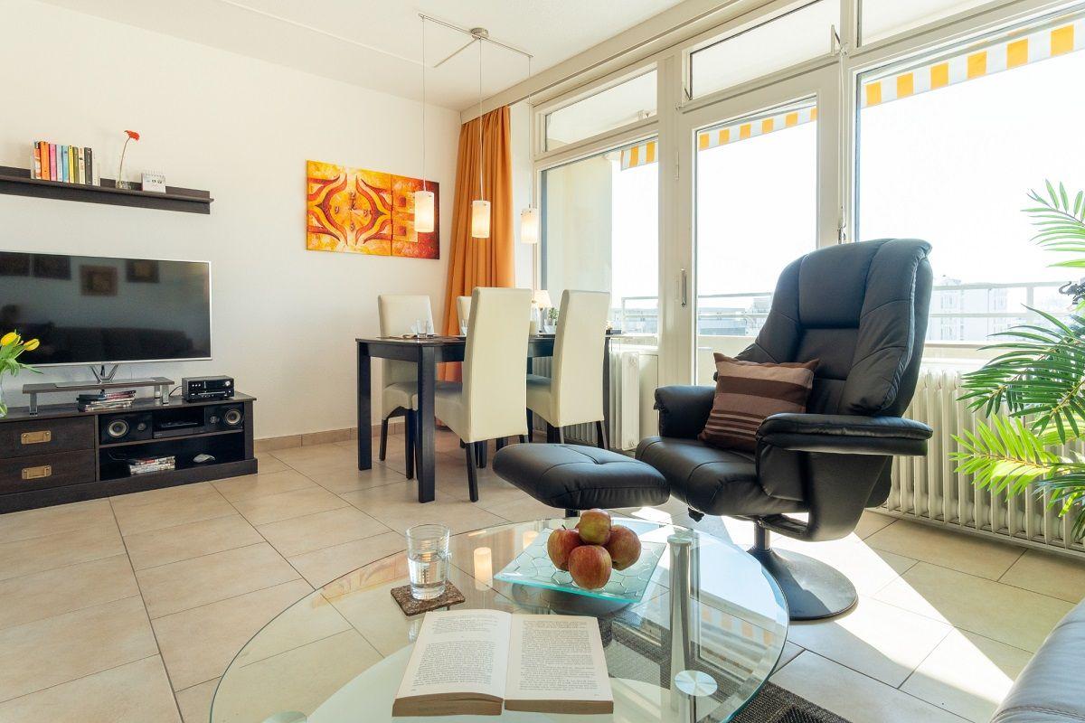 Wohnzimmer mit Essbereich, TV, Sessel und Glas-Tisch
