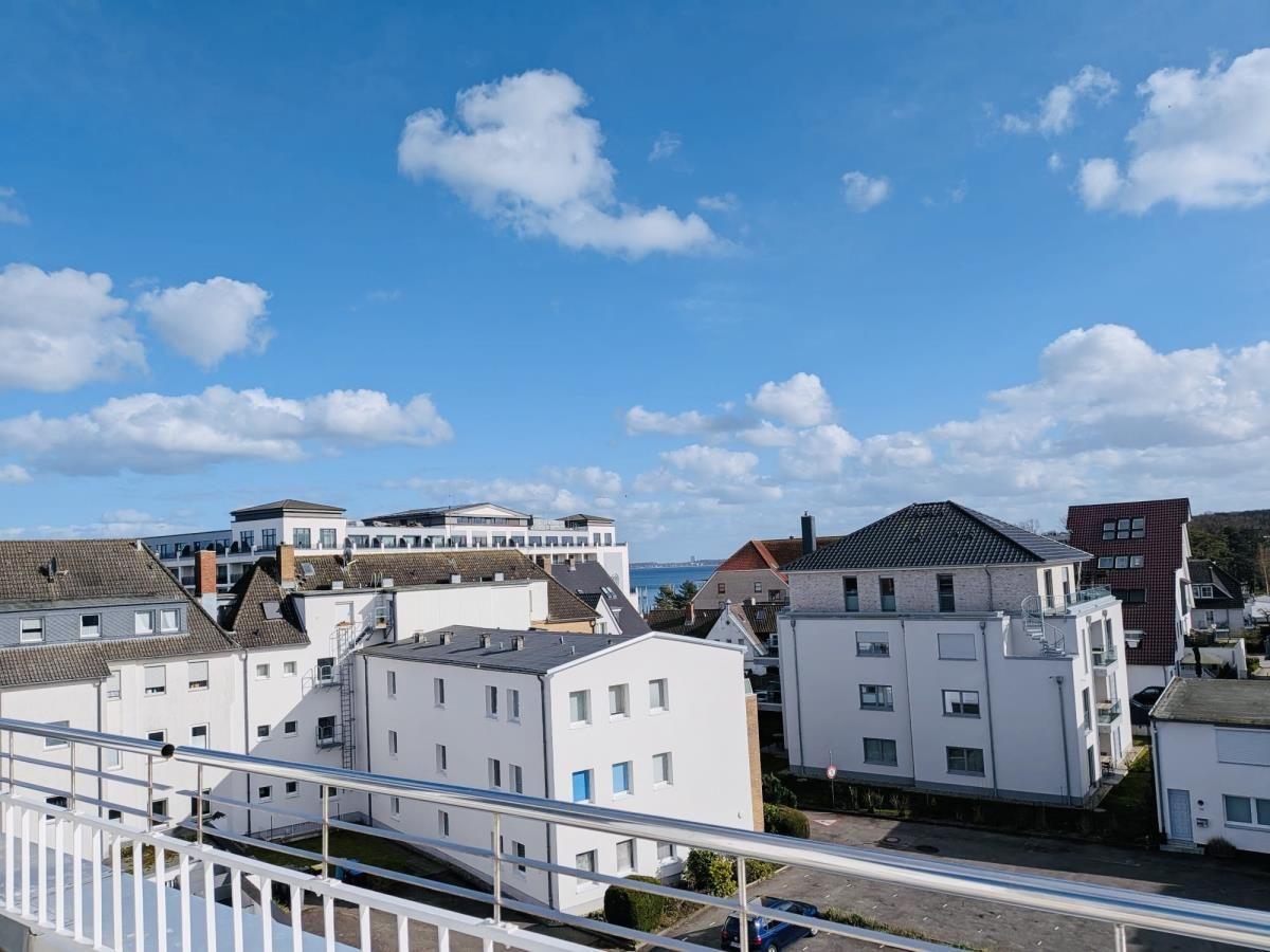 Blick von Balkon auf Wohnhäuser und Himmel mit weißen Wolken.