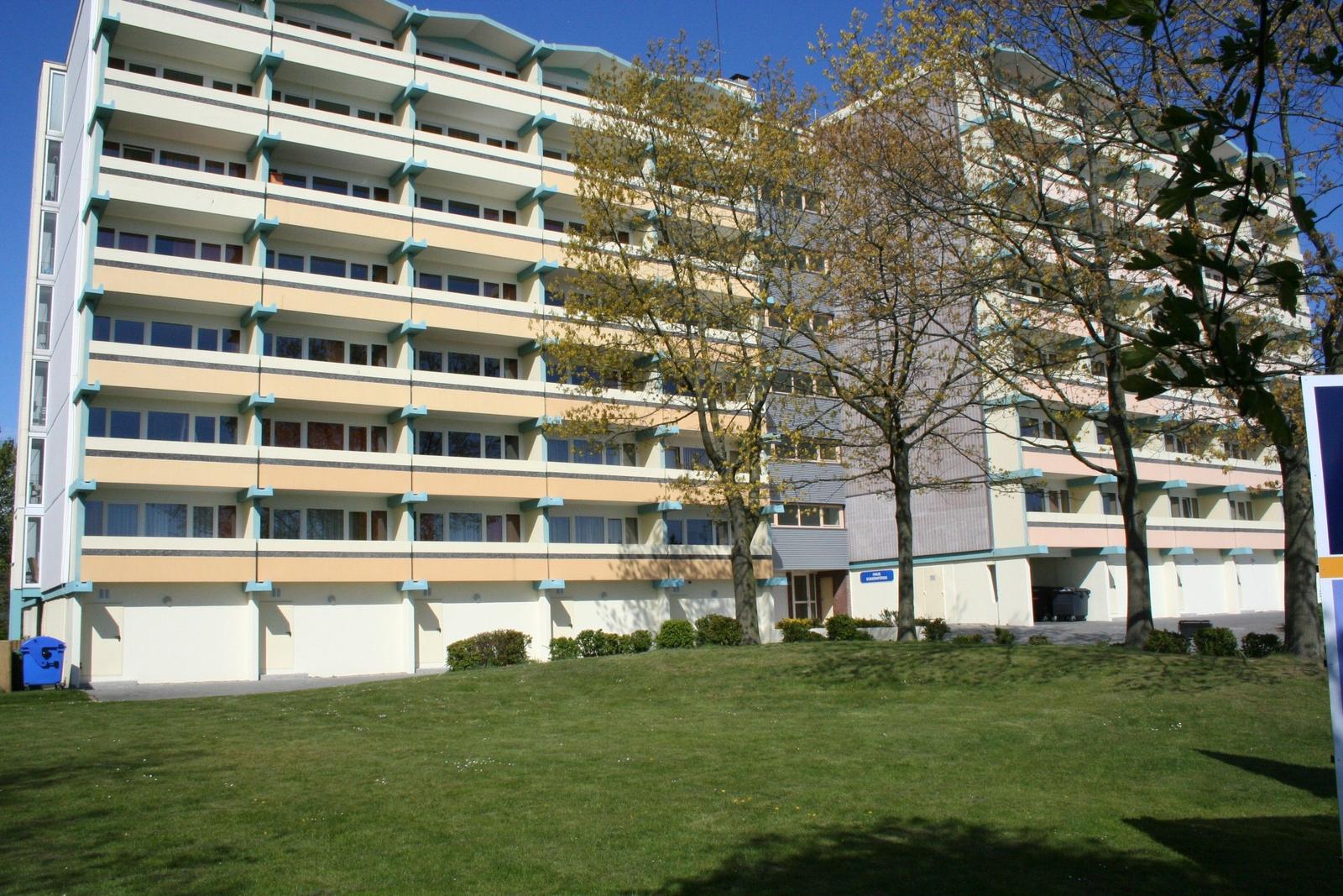Hochhaus mit Balkonen und grünem Rasen vorne
