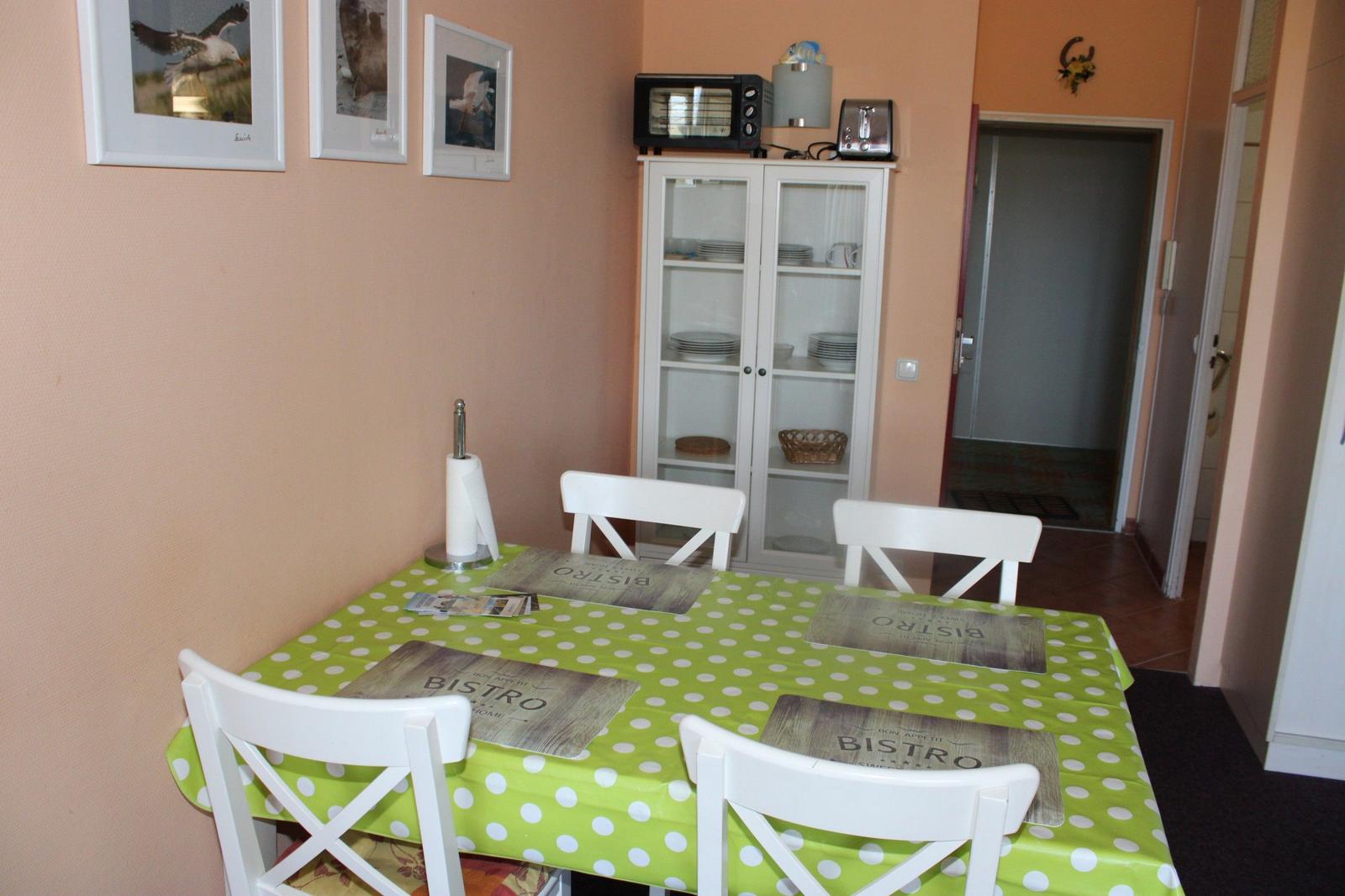 Esszimmer mit Tisch, Stühlen und Küchenschränken.