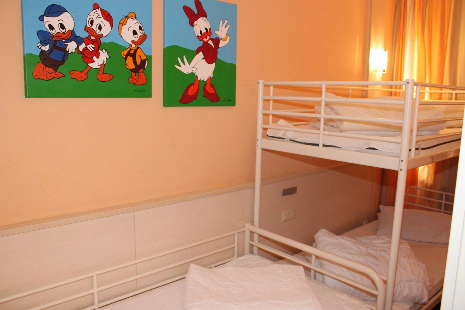 Zimmer mit Doppelstockbett und Wandbildern von Entenfiguren.