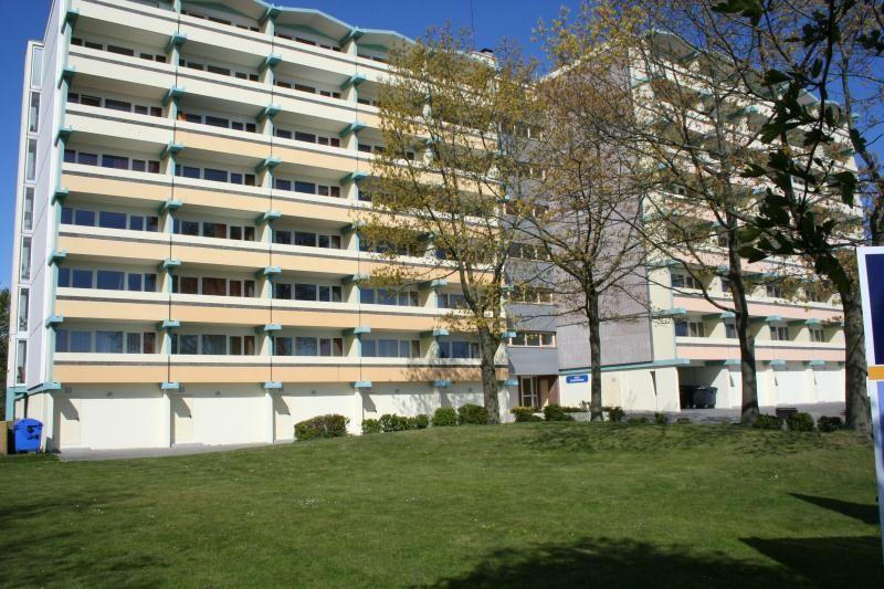 Hochhaus mit Balkonen und grünem Rasen vorne