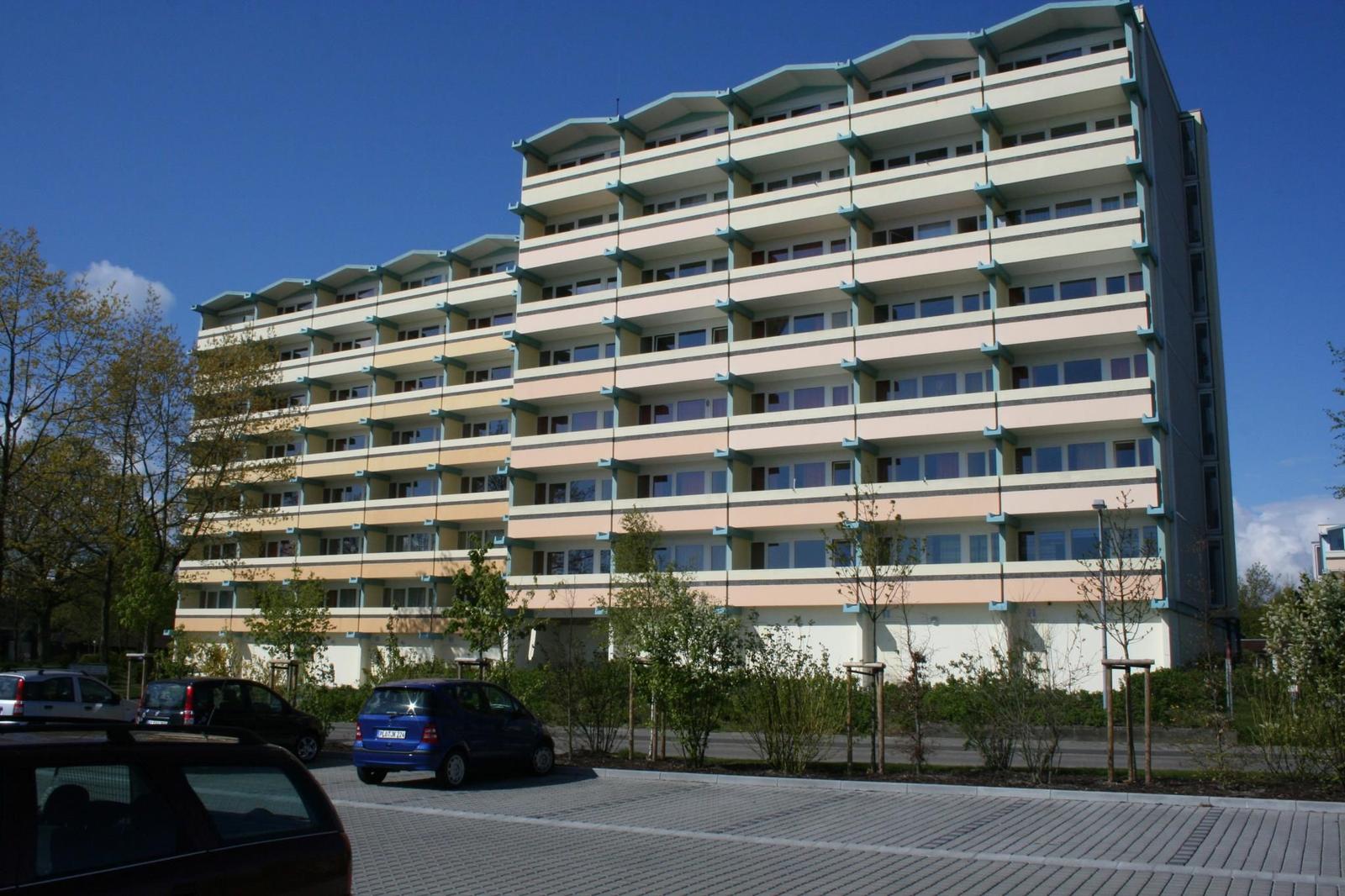 Hochhaus mit Balkonen und Parkplatz vorne