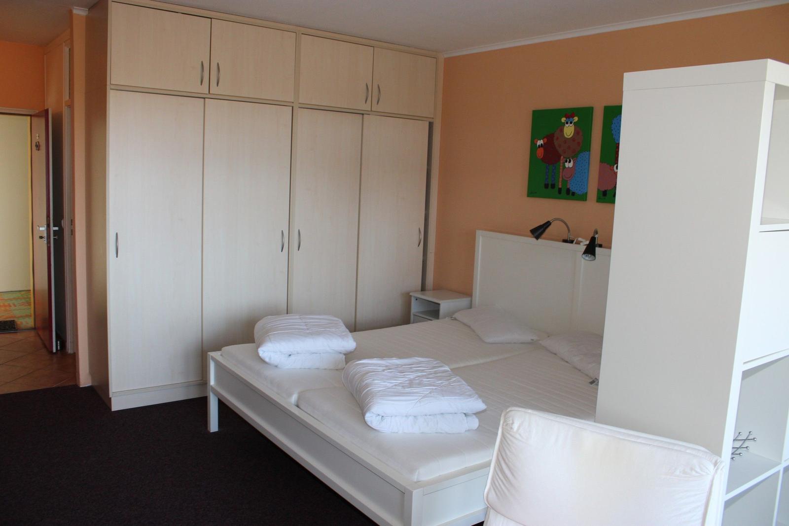 Schlafzimmer mit Doppelbett, Kleiderschrank und Wandbildern