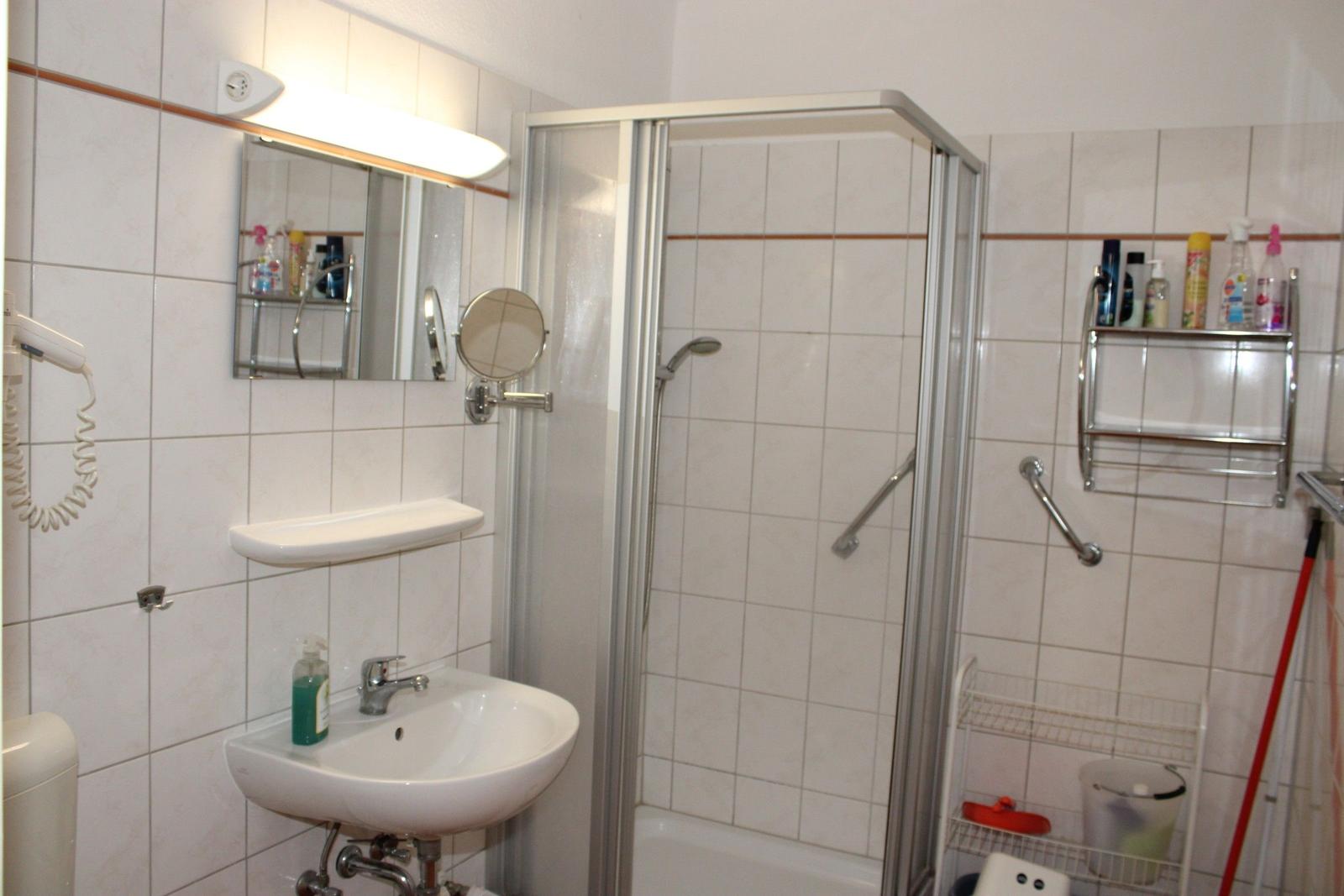 Badezimmer mit Dusche, Waschbecken und Spiegel