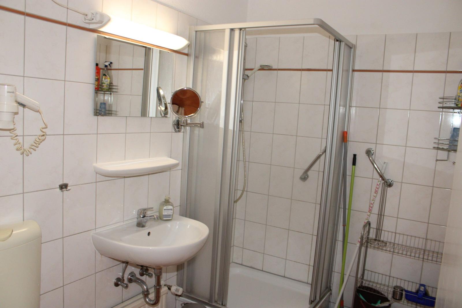 Badezimmer mit Dusche, Waschbecken und Spiegel