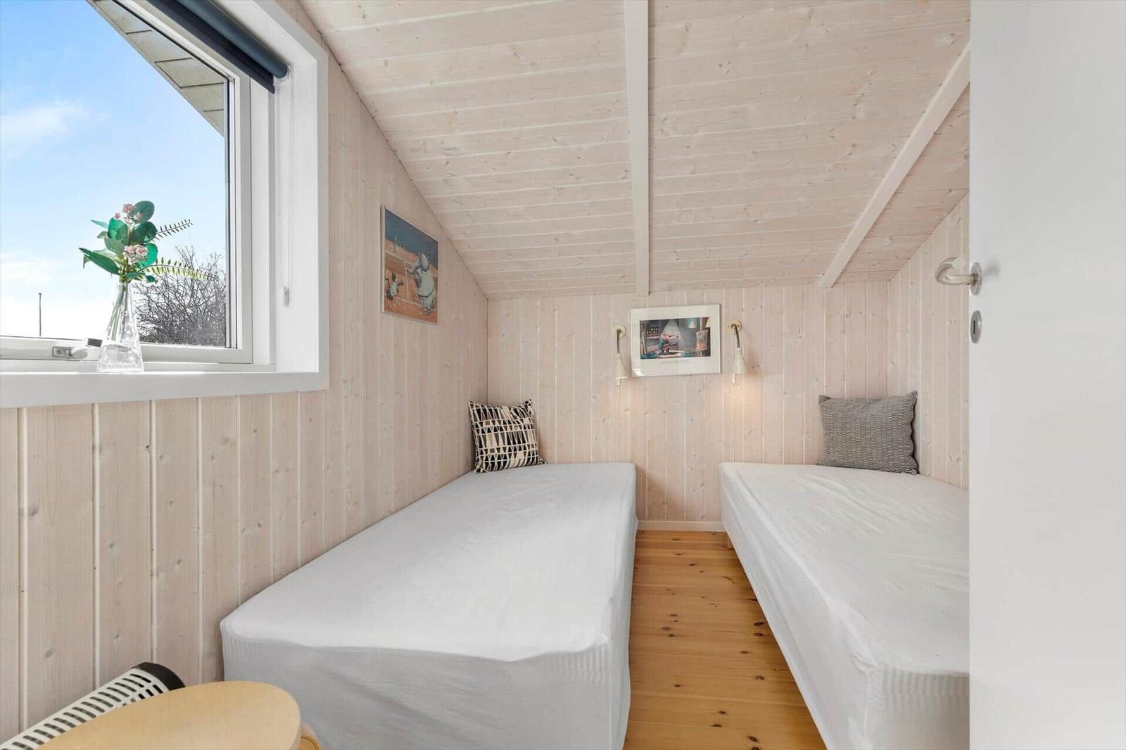 Zwei Einzelbetten in einem Holzraum mit Fenster und Wandbildern.