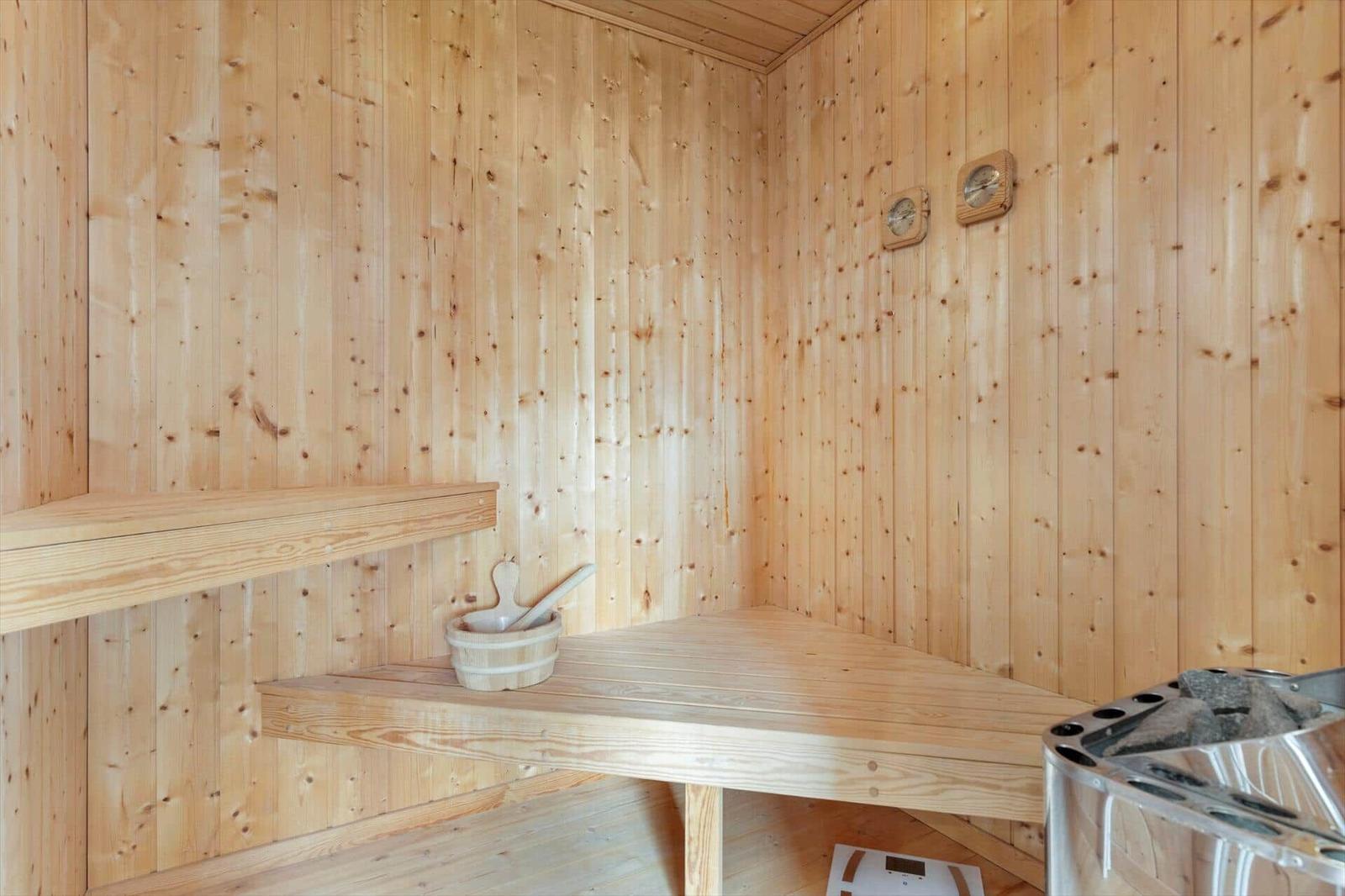 Sauna mit Holzwand, Sitzbank und Holzschale.