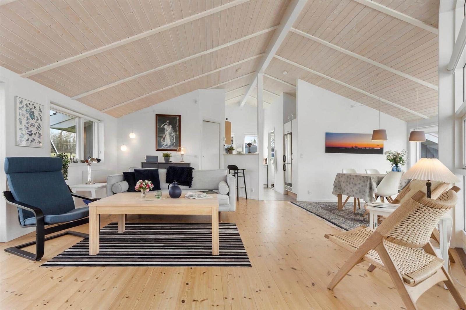 Wohn- und Essbereich mit Holzdecke, Sofa, Tisch und Stühlen.