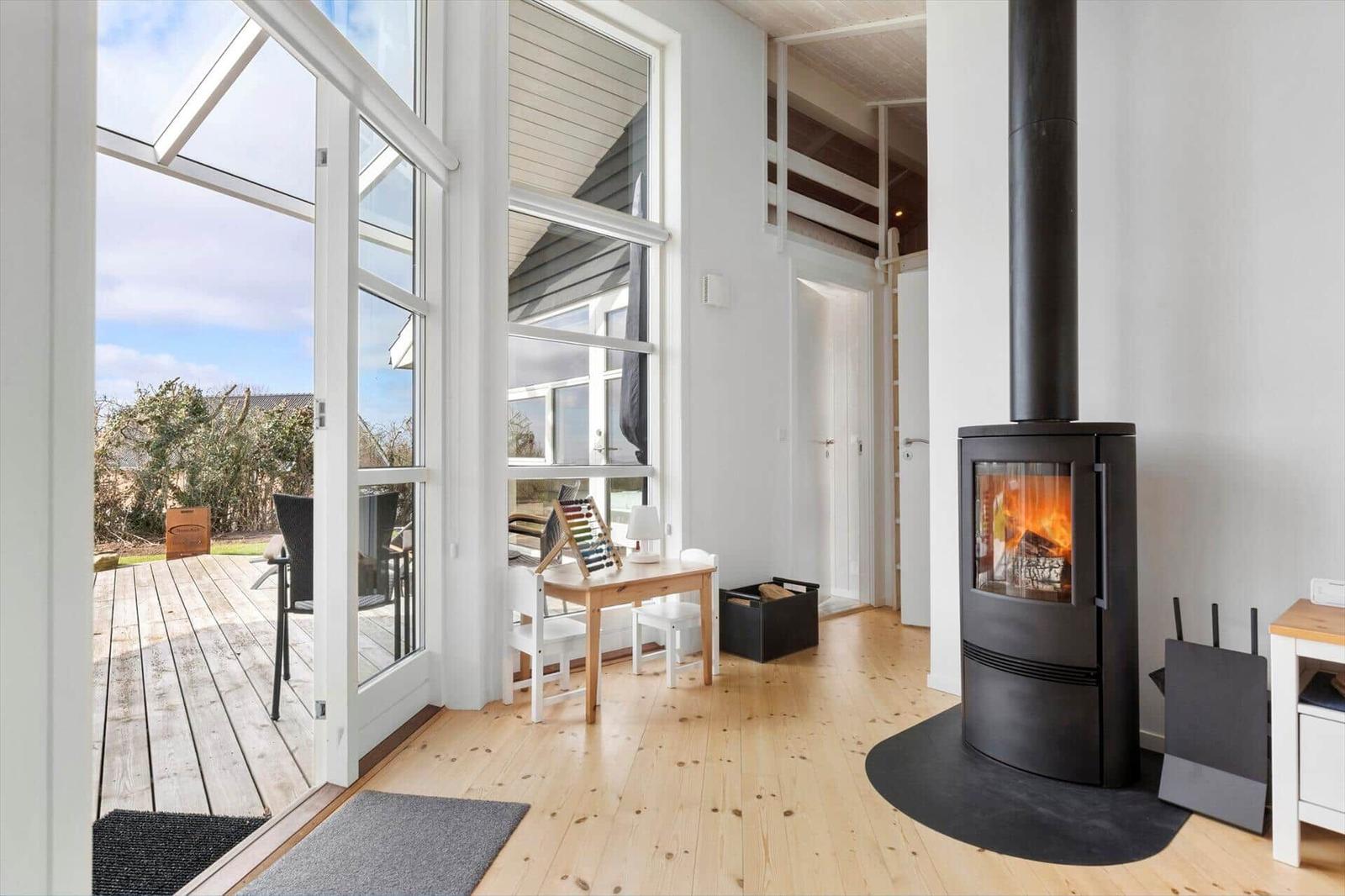Ein Raum mit Holzboden, Kamin und großem Fenster zum Balkon.