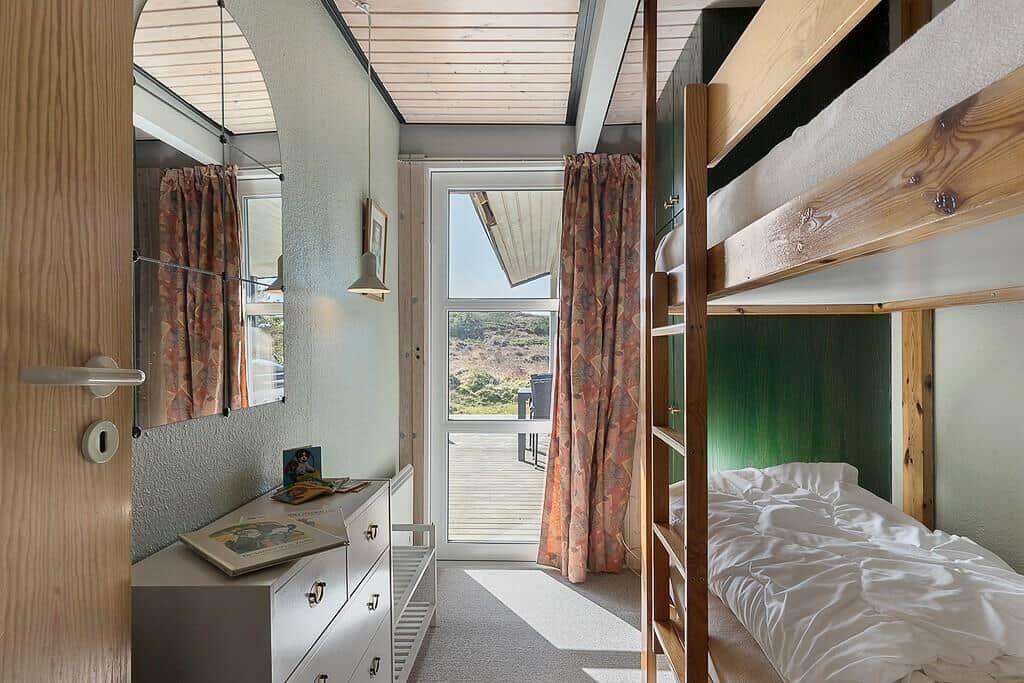 Schlafzimmer mit Doppelstockbetten, Schrank und Fenster zur Terrasse.