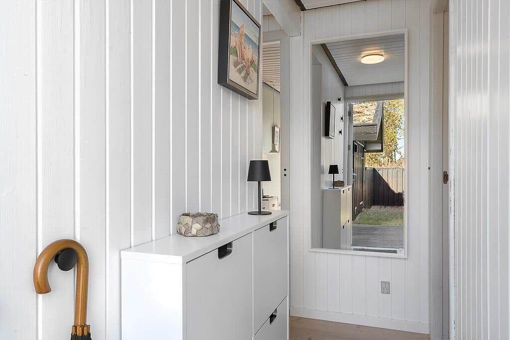 Hallenraum mit Schrank, Spiegel und Regal. Holzboden und weiße Wände.