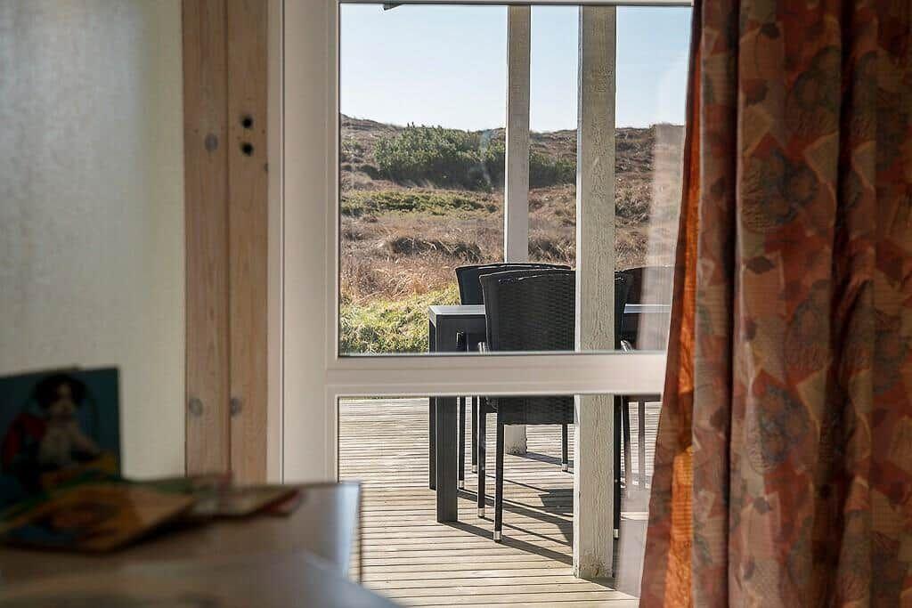Durch das Fenster ist eine Terrasse mit Stühlen und eine Wiese zu sehen.