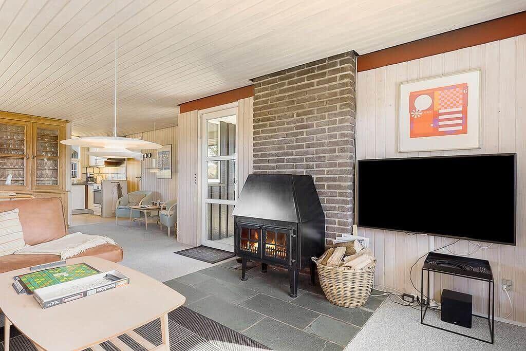 Wohnzimmer mit Kamin, Fernseher und Essbereich im Hintergrund.