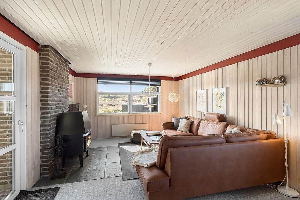 Wohnzimmer mit braunem Sofa, Kamin und Fensterblick