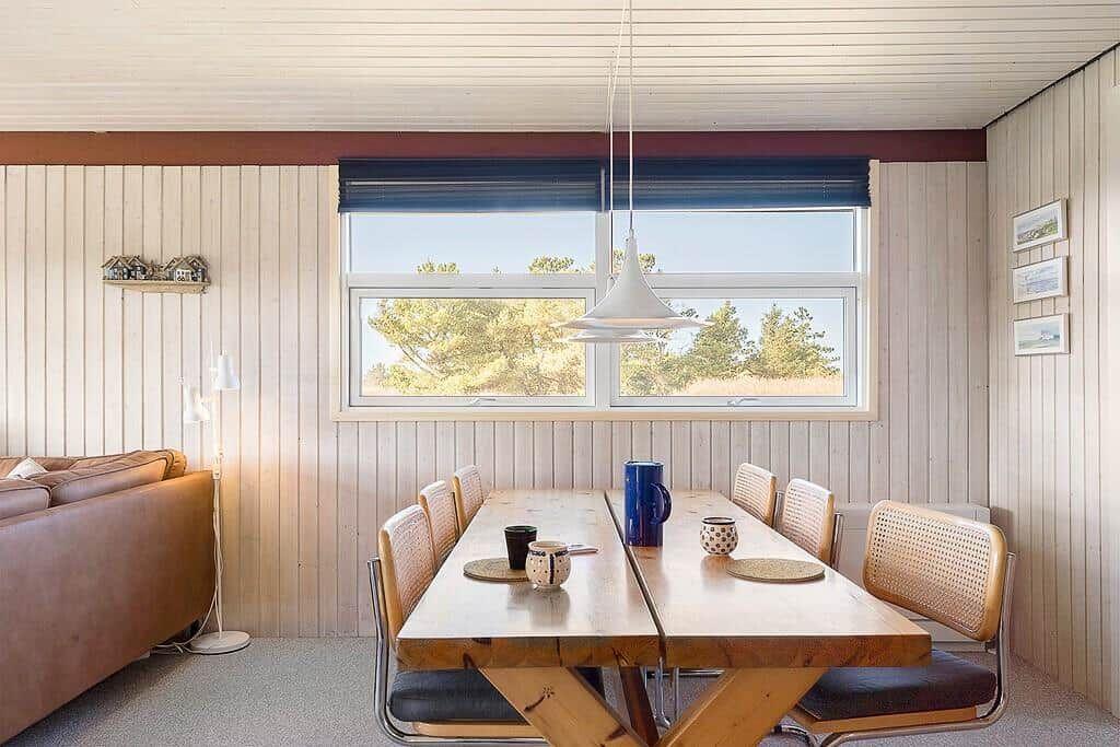 Esszimmer mit Holztisch, Stühlen und Fensterblick auf Bäume
