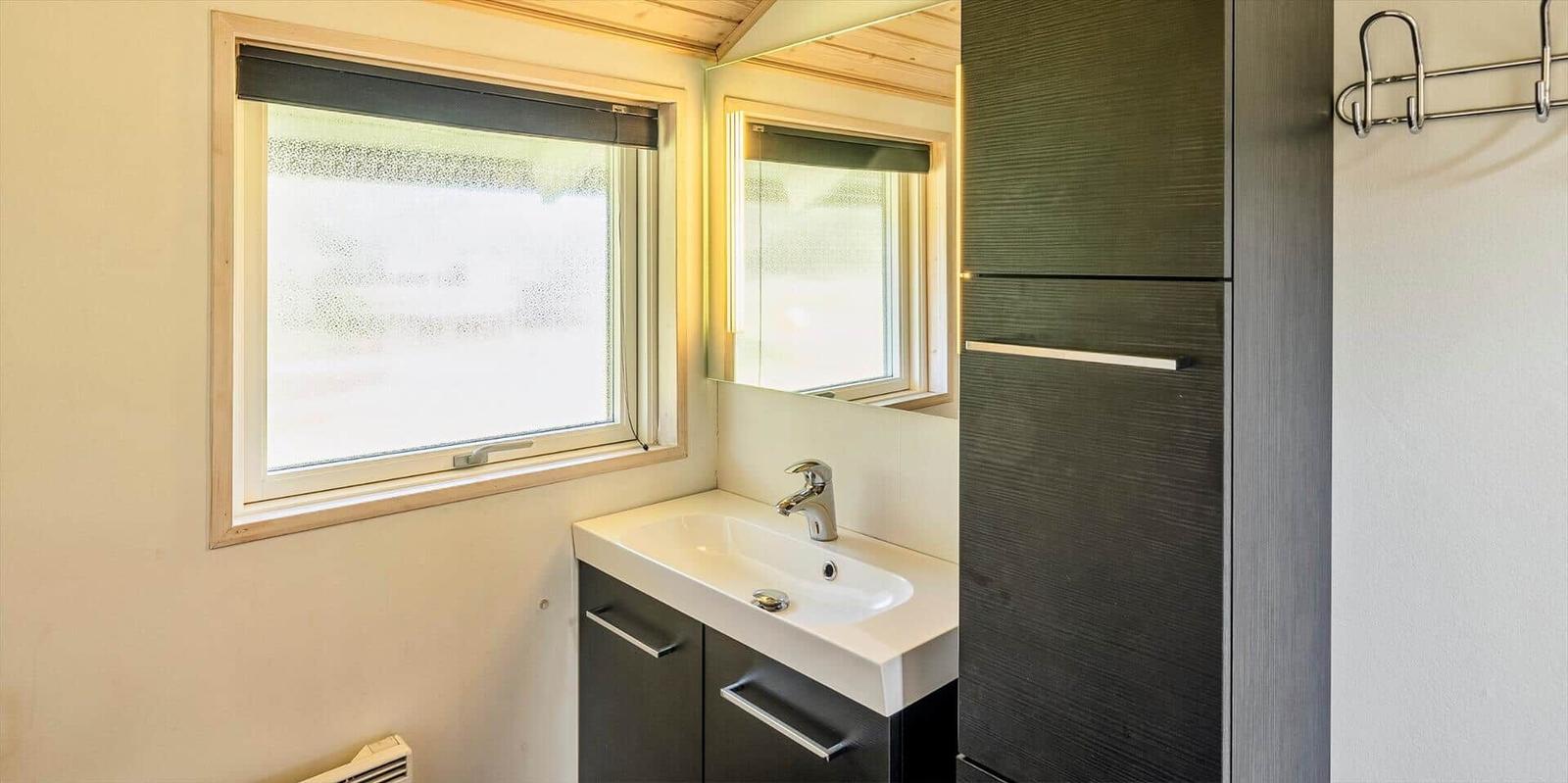Badezimmer mit Waschbecken, Spiegel und Fenster.
