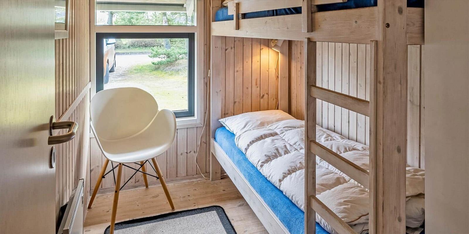 Zimmer mit Kletterbett, weiße Sitzgelegenheit und Fensterblick.