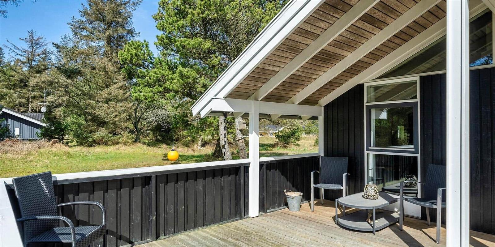 Terrasse mit Sitzgelegenheiten und Blick auf Wald und Gras