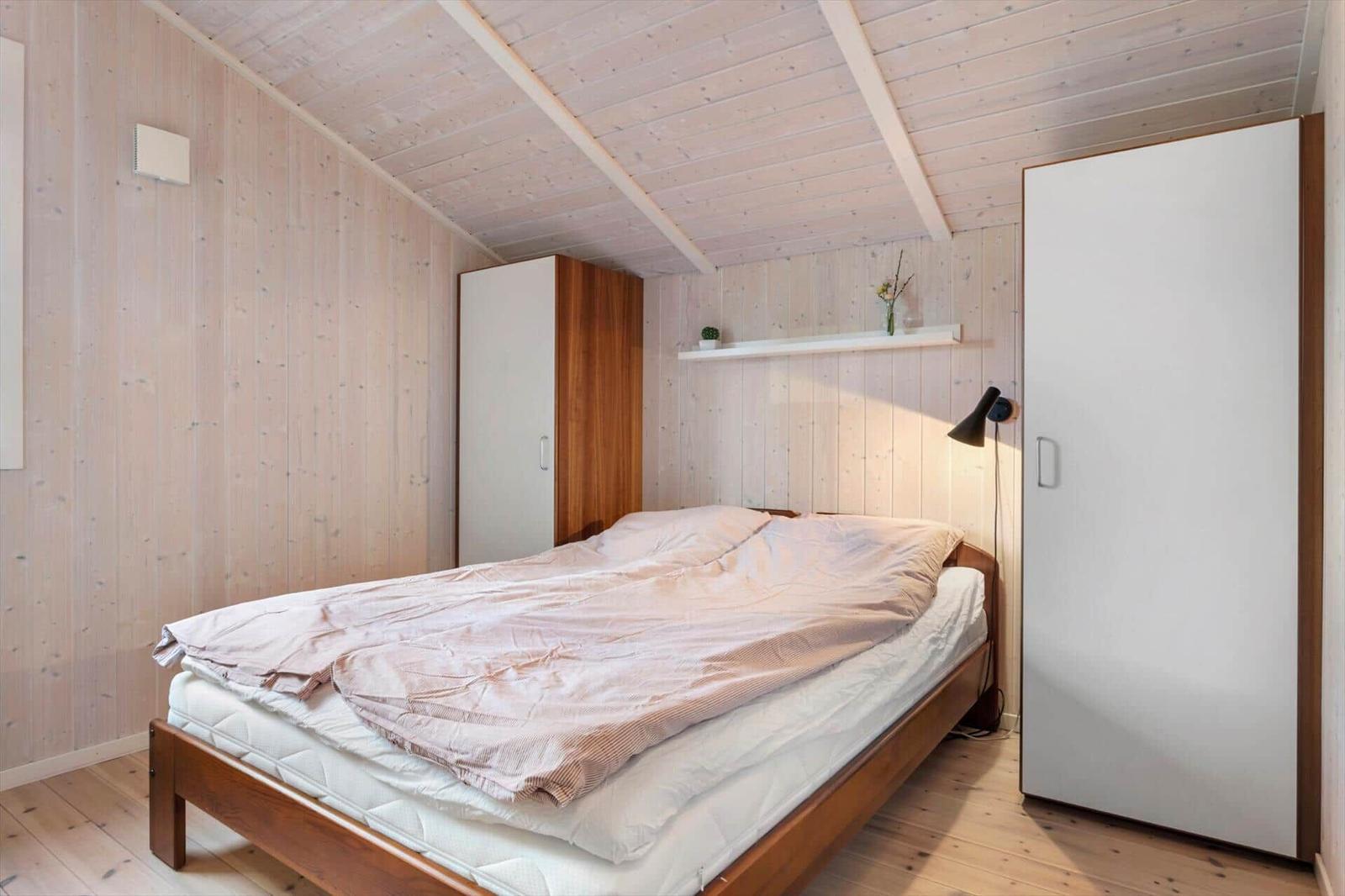 Schlafzimmer mit Holzwand, Bett und Schränken